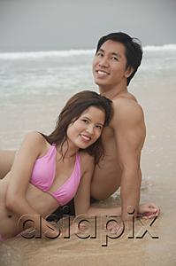 AsiaPix - Couple sitting on beach, looking at camera, portrait
