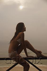 AsiaPix - Woman sitting on beach, looking away