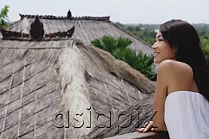 AsiaPix - Young woman leaning on railing looking out at thatched roofs