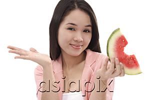 AsiaPix - Young woman holding a slice of watermelon, looking at camera