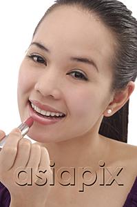 AsiaPix - Young woman applying lipstick, smiling