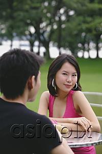 AsiaPix - Woman smiling at camera, arms crossed, man in foreground