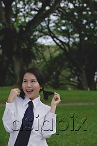 AsiaPix - Young woman in school uniform, standing in park, touching her hair