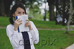 AsiaPix - Young woman in school uniform, book covering face