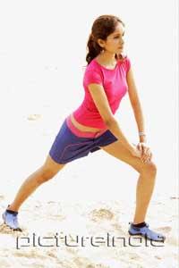 PictureIndia - Young woman at the beach, stretching