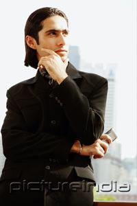 PictureIndia - Businessman with arms crossed and hand on chin, looking away