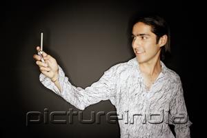PictureIndia - Young man looking at mobile phone, smiling