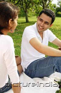 PictureIndia - Couple sitting on picnic blanket, looking at each other