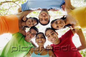 PictureIndia - Group of young adults arms around each other, looking down at camera