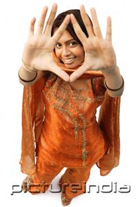 PictureIndia - Woman in Indian clothing, holding hands up and looking at camera through them