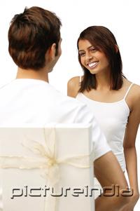 PictureIndia - Man holding present behind his back, woman smiling in front of him