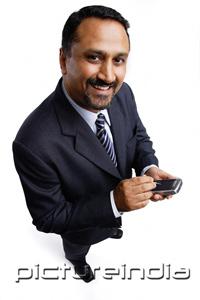 PictureIndia - Businessman holding PDA, smiling