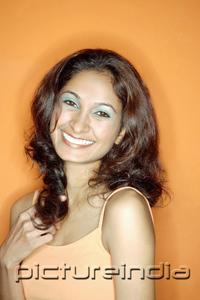 PictureIndia - Young woman in orange tank top, against orange background