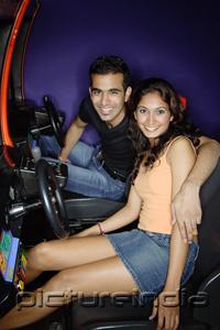 PictureIndia - Couple in a video game arcade, smiling at camera