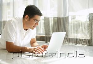 PictureIndia - Man using laptop at home