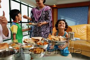 PictureIndia - Family of four having a meal at home, mother feeding son