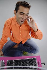PictureIndia - Man sitting in front of laptop, using mobile phone
